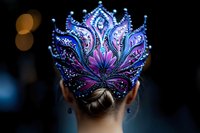 Ornate fantasy crown in purple and blue hues with intricate beading and crystal details adorns elegant updo hairstyle, photographed from behind against dark background.