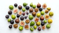 Fresh figs in various stages of ripeness arranged on white background, whole and halved fruits showing interior flesh, suitable for food styling and culinary content.