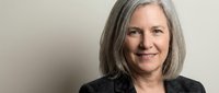 Confident mature businesswoman with gray hair smiling in professional blazer against neutral background for corporate and leadership concepts.
