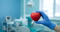 Medical professional in blue gloves holding red heart in modern hospital operating room for cardiac surgery and healthcare concept.
