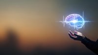 Human hand reaching toward glowing brain with energy waves on gradient background representing artificial intelligence and neural networks.