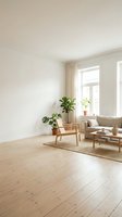 Bright minimalist living room with wooden flooring, beige sofa, mid-century chair, potted plants by windows with cream curtains, and empty white walls for design projects.
