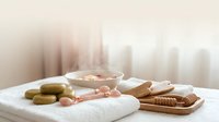 Spa wellness setup with natural soap bars, wooden accessories and soft towels creating peaceful relaxation atmosphere for self-care rituals.