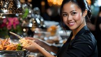 Young Asian female server presenting gourmet dish in upscale restaurant with elegant bokeh lighting and professional hospitality service atmosphere.
