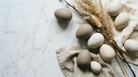 Natural organic eggs in neutral earth tones with dried wheat stalks on marble surface, rustic farm fresh concept for healthy cooking and baking projects.