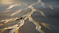 Frayed denim fabric with golden threads unraveling in warm sunlight, showing detailed textile texture and worn edges for fashion and crafting projects.