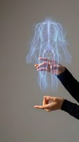 Hands protecting glowing human body hologram with highlighted spine and nervous system for healthcare and medical technology concepts.
