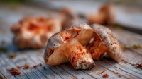 Fresh wild mushrooms with earthy brown caps and orange-red stems on rustic wooden surface, perfect for culinary photography and seasonal food content.