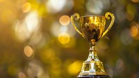Golden trophy cup on blurred bokeh background with warm sunlight creates inspiring atmosphere of victory and achievement in sports or business.