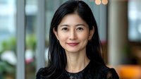 Young Asian businesswoman with confident smile wearing black attire in modern office setting with soft bokeh background. Professional corporate portrait.