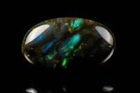 Polished opal gemstone displaying vibrant blue and green fire patterns against dark background, macro photography showcasing natural mineral iridescence.