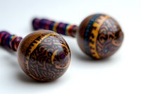 Wooden maracas with intricate tribal patterns and colorful woven handles on white background, traditional Latin American percussion instruments for music and dance.