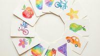 Colorful watercolor children drawings arranged in circle on white background featuring car, apple, star, flower and other kid art elements for educational materials.
