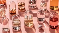 Glass vials with colorful liquids casting long shadows on pink background, minimalist luxury cosmetic product photography for beauty and wellness industry.