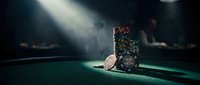 Casino poker chips stacked on green felt table under dramatic spotlight creating moody gambling atmosphere for entertainment and gaming concepts.