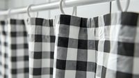 Black and white buffalo plaid curtains hanging on metal curtain rod against light background, creating modern farmhouse style decor element with classic checkered pattern.