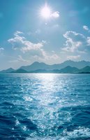 Sunlight sparkles on blue ocean waves with mountain silhouettes on horizon and white clouds in turquoise sky, creating serene seascape atmosphere.