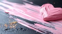 Pink creamy paint smear with gold glitter particles on dark background, artistic cosmetic texture showing smooth glossy consistency and metallic sparkle.