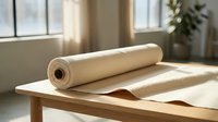 Natural kraft paper roll unrolled on wooden table in bright sunlit room with window light. Eco-friendly packaging material for wrapping gifts and crafts.