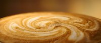 Latte art with caramel and cream swirls in hot coffee cup, overhead view for cafe menu design and beverage marketing.