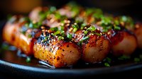 Glazed Asian-style scallops garnished with black sesame seeds and fresh chopped herbs on dark plate, close-up macro shot with selective focus and rich colors.