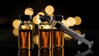 Medical vials with amber liquid and syringe for pharmaceutical research and healthcare treatment against bokeh lights background.