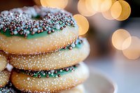 Freshly baked sugar cookies decorated with chocolate coating and mint sprinkles stacked together, with soft bokeh lights creating festive holiday atmosphere.