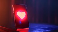 Glowing heart symbol on smartphone screen with dramatic red and blue lighting on dark background, modern love and technology concept.