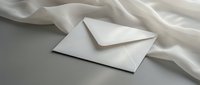 White envelope on elegant silk fabric background for luxury correspondence and wedding invitations.