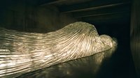 Large-scale contemporary art installation featuring flowing metallic fabric sculpture in dimly lit gallery space creating dramatic shadows and reflections.