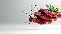 Fresh raw beef steaks floating in air with rosemary sprig and scattered peppercorns against light background, creative food photography for restaurant menu.