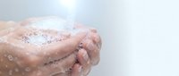 Hands washing with soap and water creating foam bubbles for hygiene and cleanliness routine against clean background.