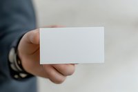 Male professional in business attire holding blank white business card for corporate branding, networking, and marketing presentations.