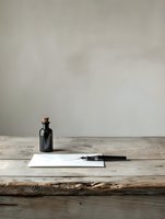 Fountain pen resting on blank white paper with dark glass ink bottle on rustic wooden table against neutral wall background, suitable for writing, stationery, and office design projects.