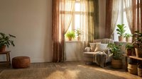 Cozy living room interior with natural sunlight streaming through windows, comfortable armchair, houseplants and warm earth tone decor creating peaceful home atmosphere.