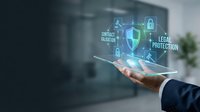 Businessman hand holding digital security shield with legal protection and contract validation icons in modern office environment.