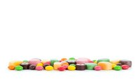 Colorful assorted candy beans scattered on white background, isolated confectionery sweets for dessert and snack designs.