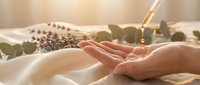 Spa wellness aromatherapy treatment with essential oil dropper and cupped hands in natural sunlight for relaxation and self-care rituals.