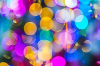 Vibrant defocused bokeh lights creating a dreamy abstract background with pink, yellow, blue and turquoise circles perfect for festive designs and holiday decorations.