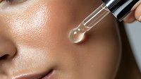 Closeup of glowing moisturized skin with glass dropper applying transparent serum. Dewy complexion showing skincare and beauty treatment results for cosmetic advertising.
