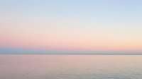Serene seascape at dawn with soft pink and blue hues reflecting on calm ocean waters, conveying tranquility and peaceful morning atmosphere for wellness and meditation content.