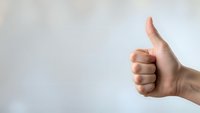 Hand showing thumbs up gesture against neutral background expressing approval, success, positive feedback and satisfaction concept.