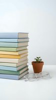 Stack of colorful books with small potted plant and eyeglasses on white surface for education and reading concepts.