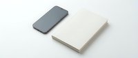 Modern smartphone and blank notebook on clean white background for business branding mockup and corporate identity design projects.