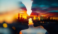 Romantic silhouette of couple about to kiss against urban skyline at sunset, with dramatic orange and purple sky creating double exposure effect.