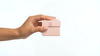 Hand holding small pink gift box on white background isolated for design use in greeting cards and promotional materials.