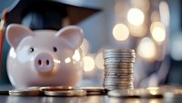 Pink piggy bank with graduation cap next to coin stack representing education savings and financial planning for college tuition costs.