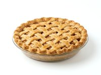 Freshly baked fruit pie with golden lattice crust in glass dish, isolated on white background for food photography, baking, and culinary design projects.