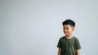 Young Asian boy wearing olive green t-shirt smiling against neutral white background, suitable for educational materials, children's campaigns, and family-oriented design projects.