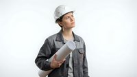 Young female construction worker or architect wearing white safety helmet and dark work shirt, holding rolled blueprints, isolated on white background for professional design use.